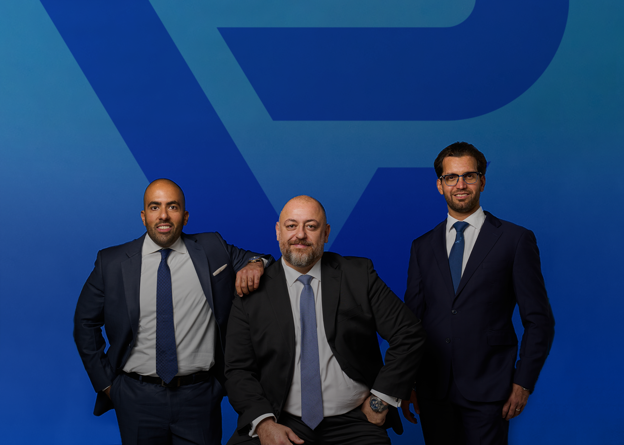 The three partners of Phoenix Venture Partners — Faris Al-Obaid, Steve Khayat and Dr. Mussaad Al-Razouki — against the electric-blue PV wall